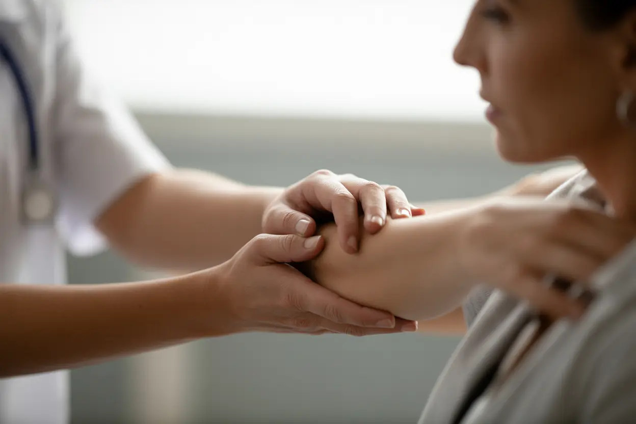 A healthcare professional's hands rest gently on a patient's arm, offering comfort and support.
