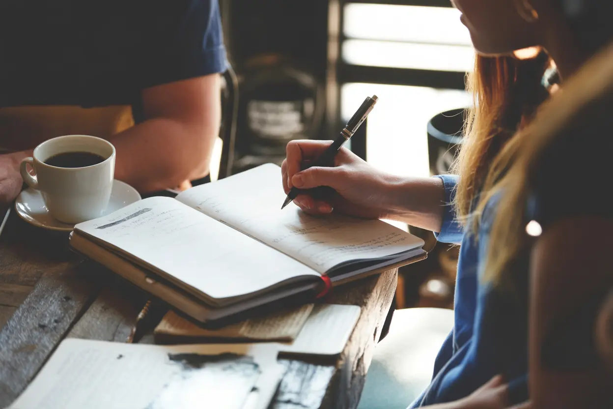 A person's hands writing in a journal at a desk, symbolizing proactive planning for recovery.