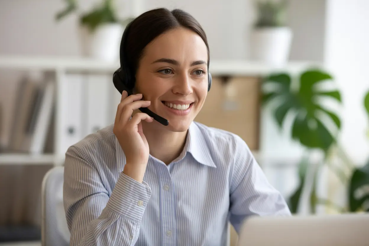 A friendly and professional admissions specialist wearing a headset and smiling, ready to help.