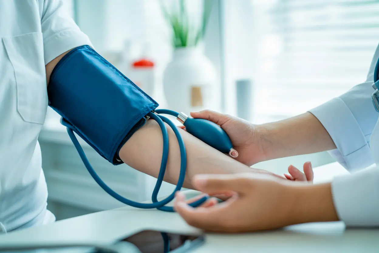 Close-up of a healthcare professional's hands placing a blood pressure cuff on a patient's arm, signifying medical monitoring and safety during treatment.